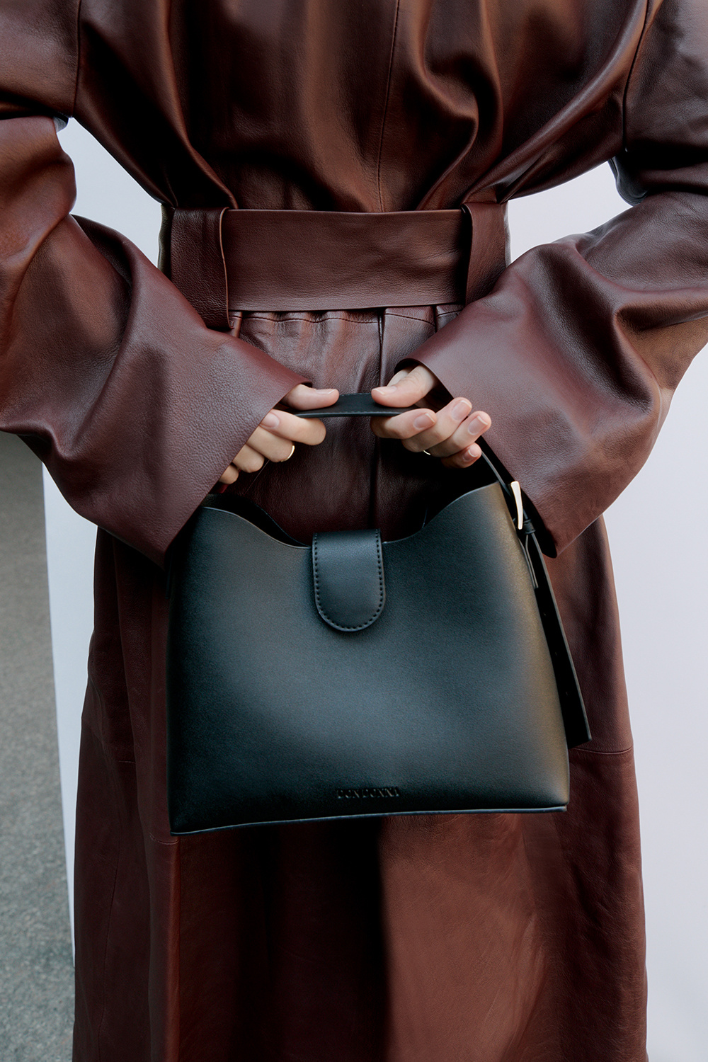 Musta käsilaukku, jossa leveä olkahihna