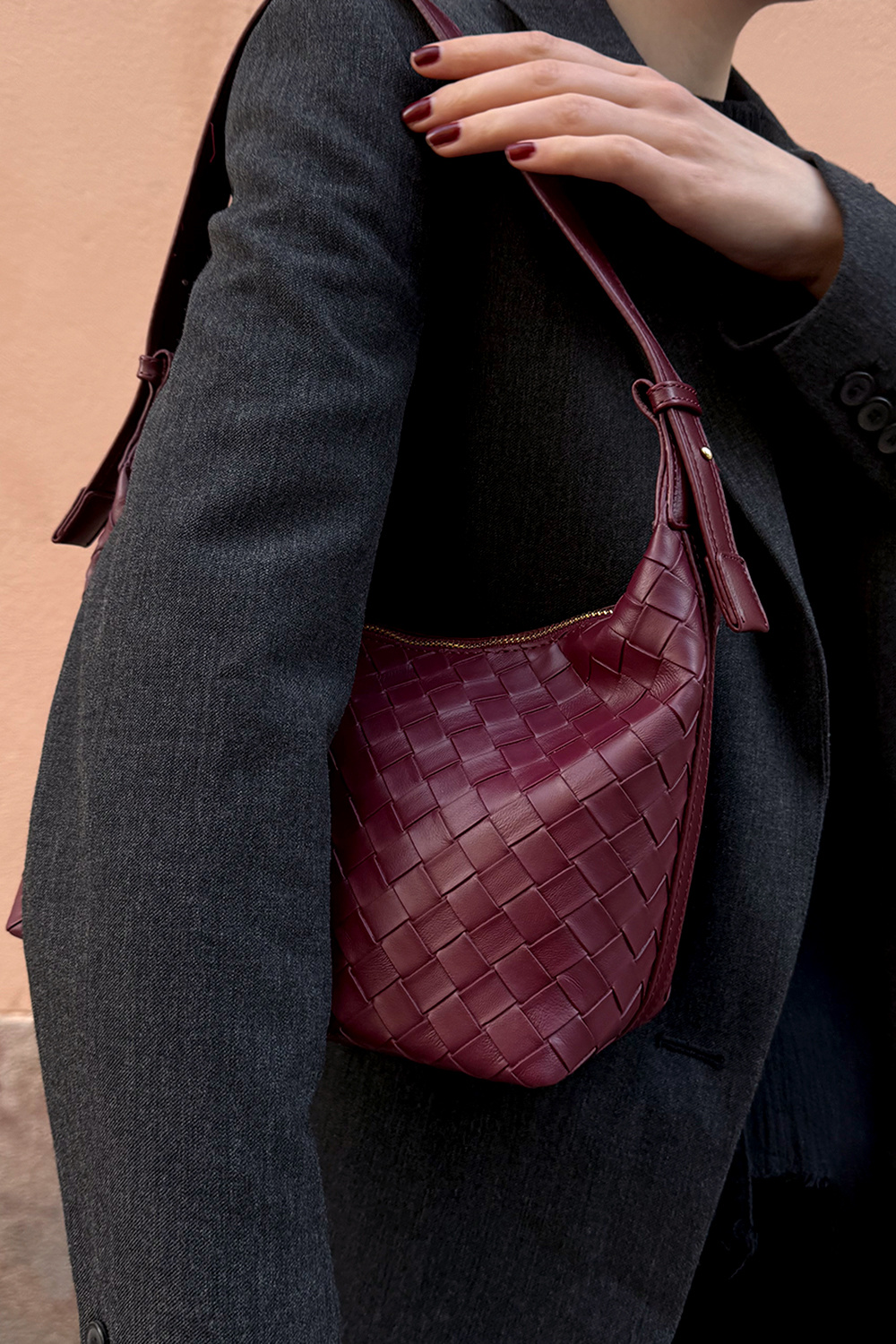 Viininpunainen käsilaukku, jossa punottu pinta