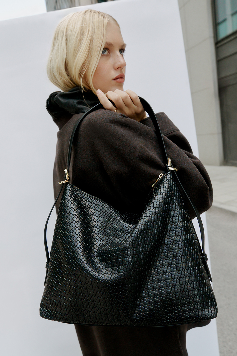 Musta hobo-tyylinen laukku punotulla pinnalla