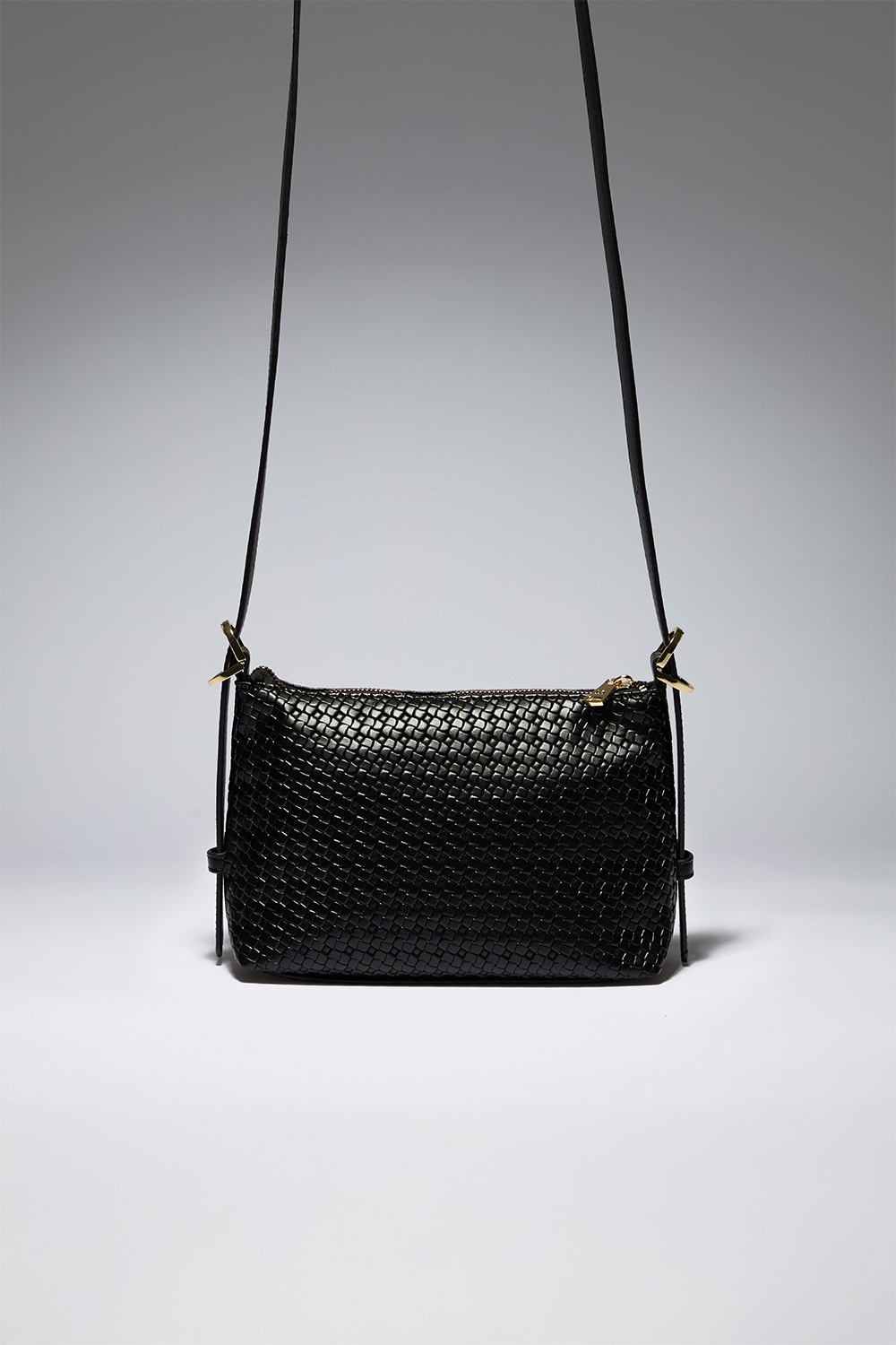 Musta crossbody-laukku, jossa punottu pinta