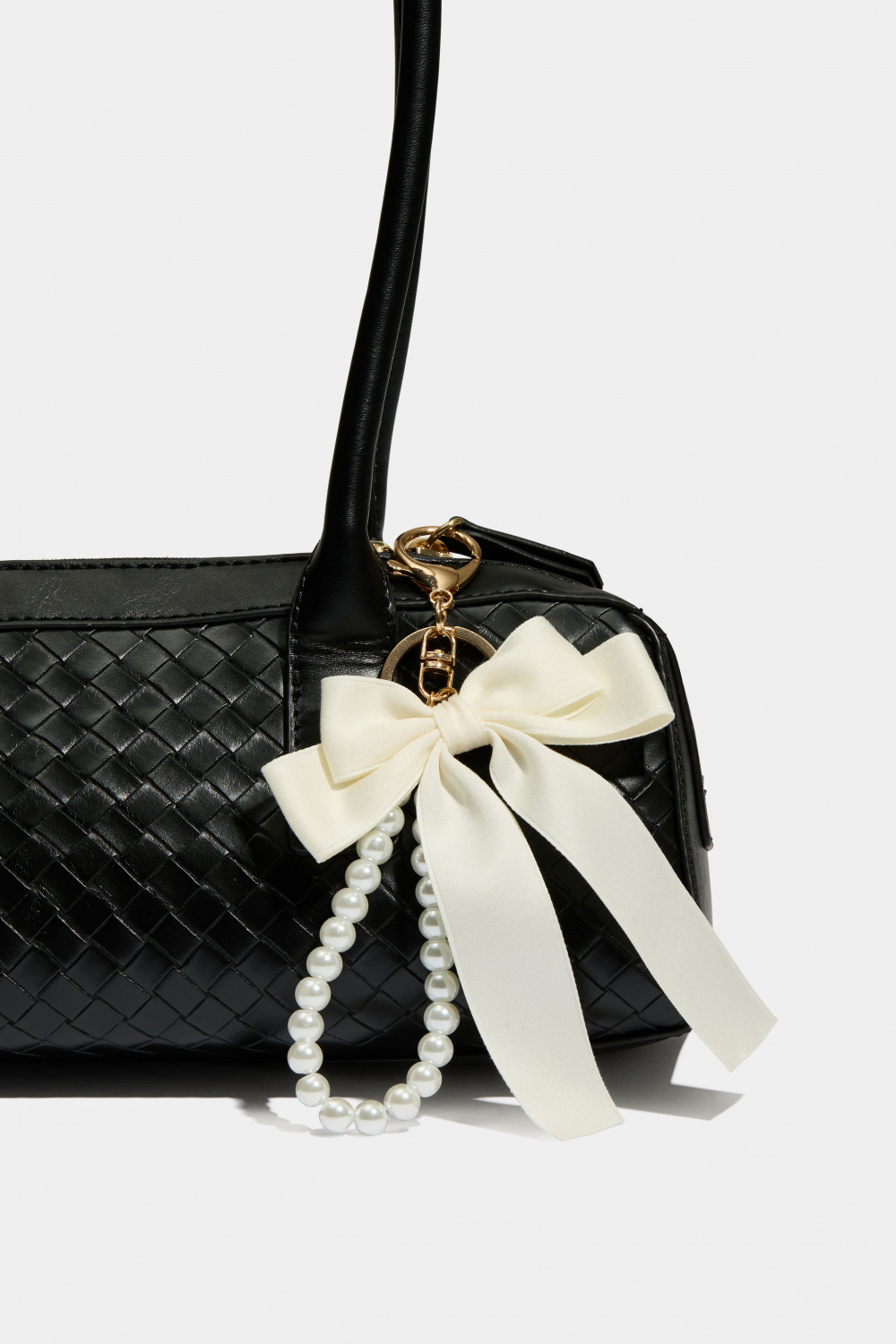 Laukkukoriste, jossa valkoinen rusetti ja helminauha