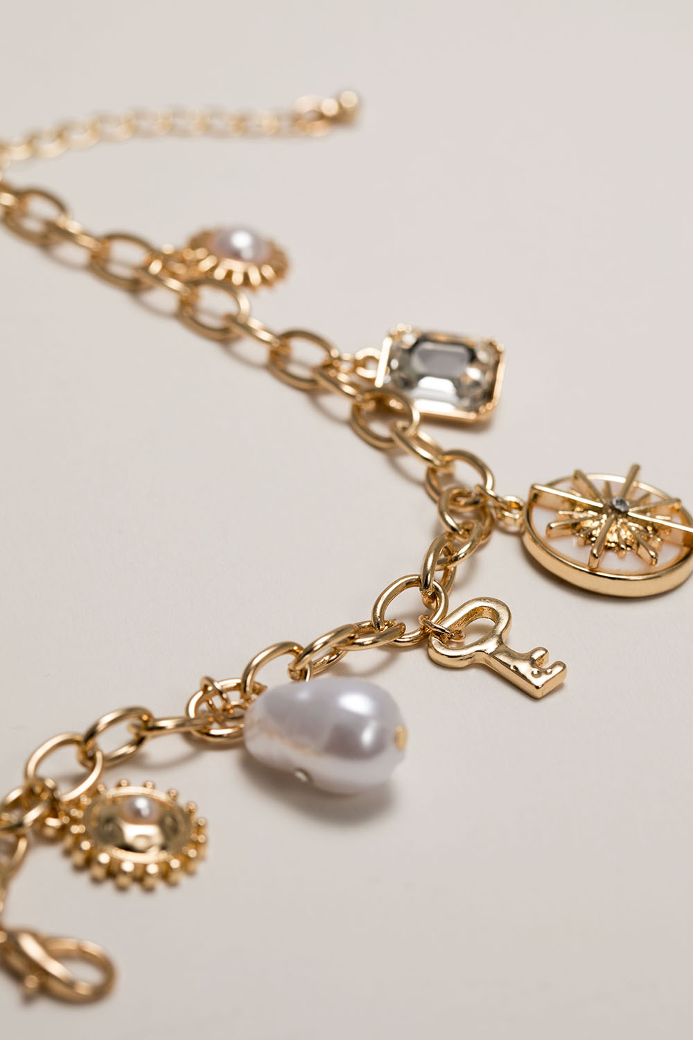 Kullanvärinen rannekoru, jossa riipuksia