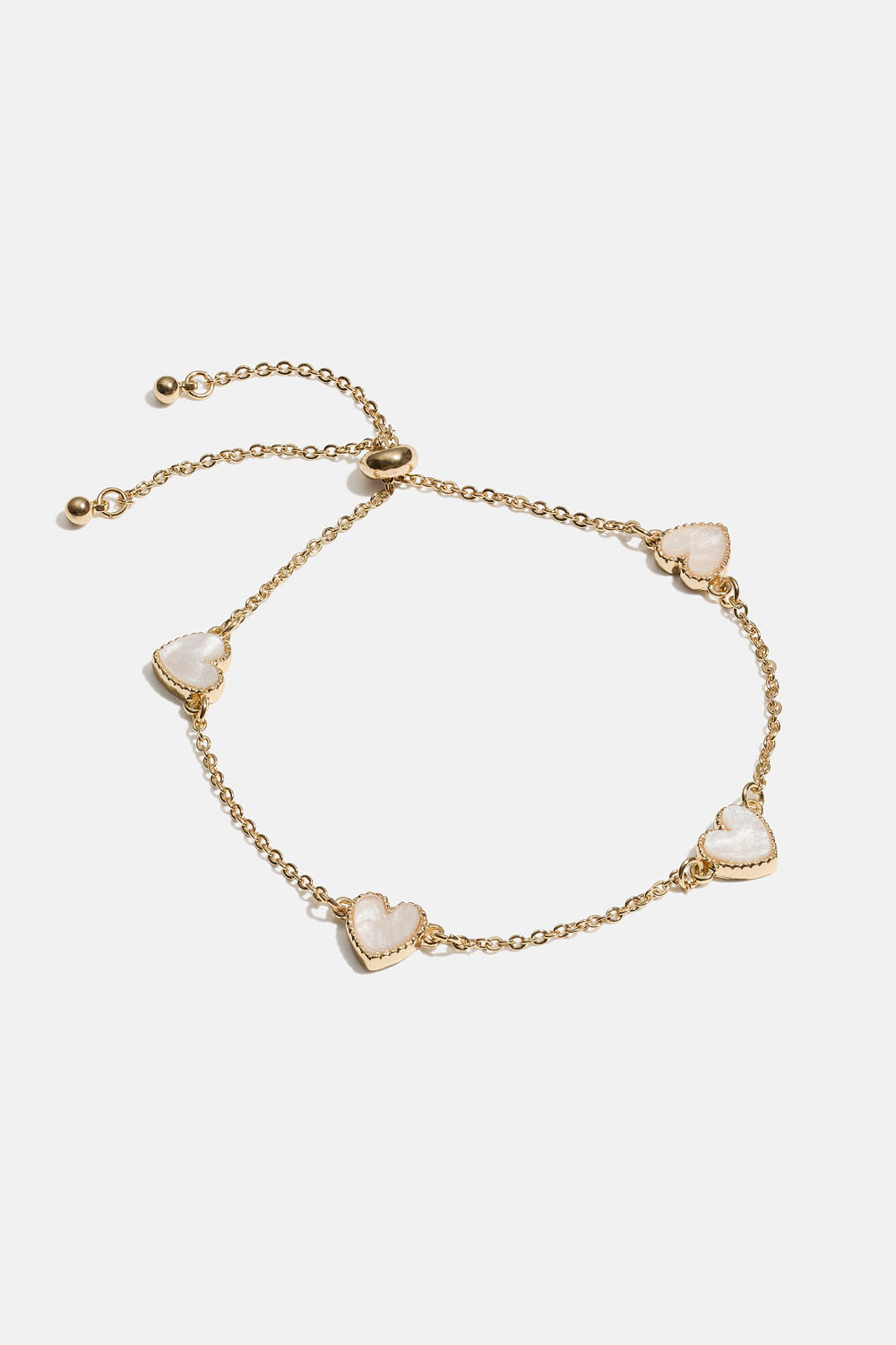 Kullanvärinen rannekoru, jossa valkoisia sydämiä