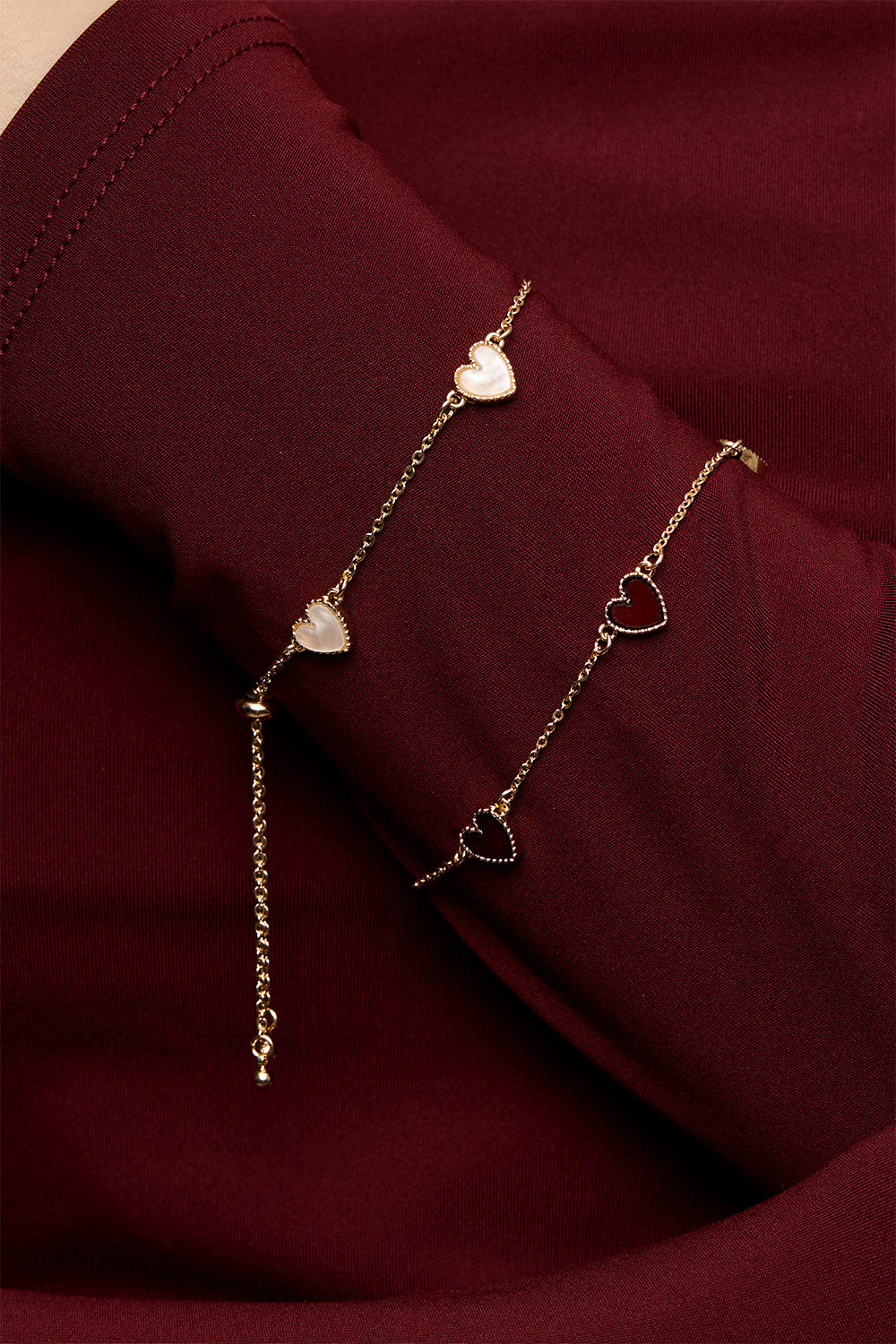 Kullanvärinen rannekoru, jossa punaisia sydämiä