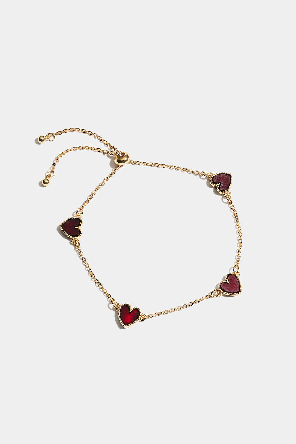 Kullanvärinen rannekoru, jossa punaisia sydämiä