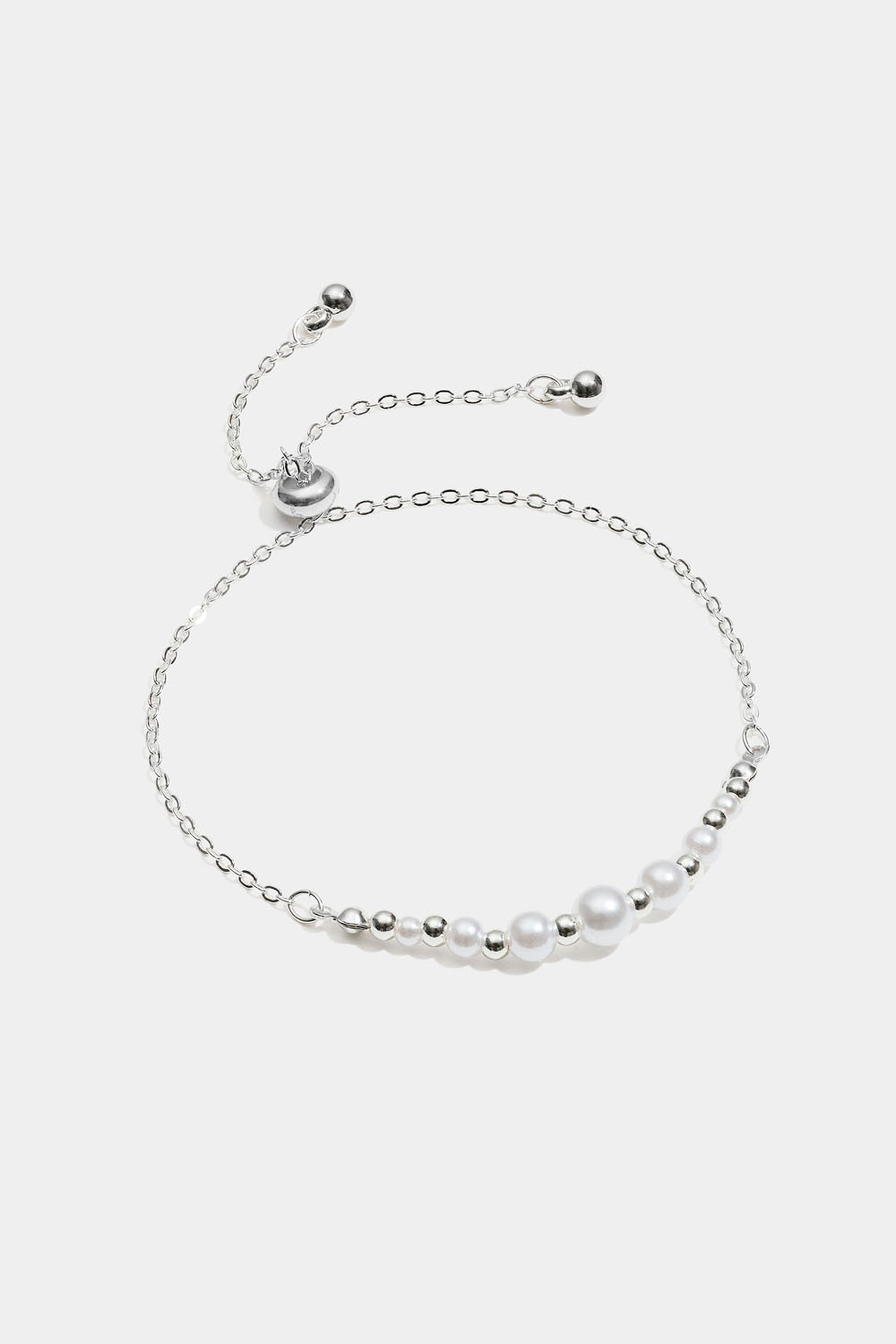 Rannekoru, jossa valkoisia ja hopeanvärisiä helmiä