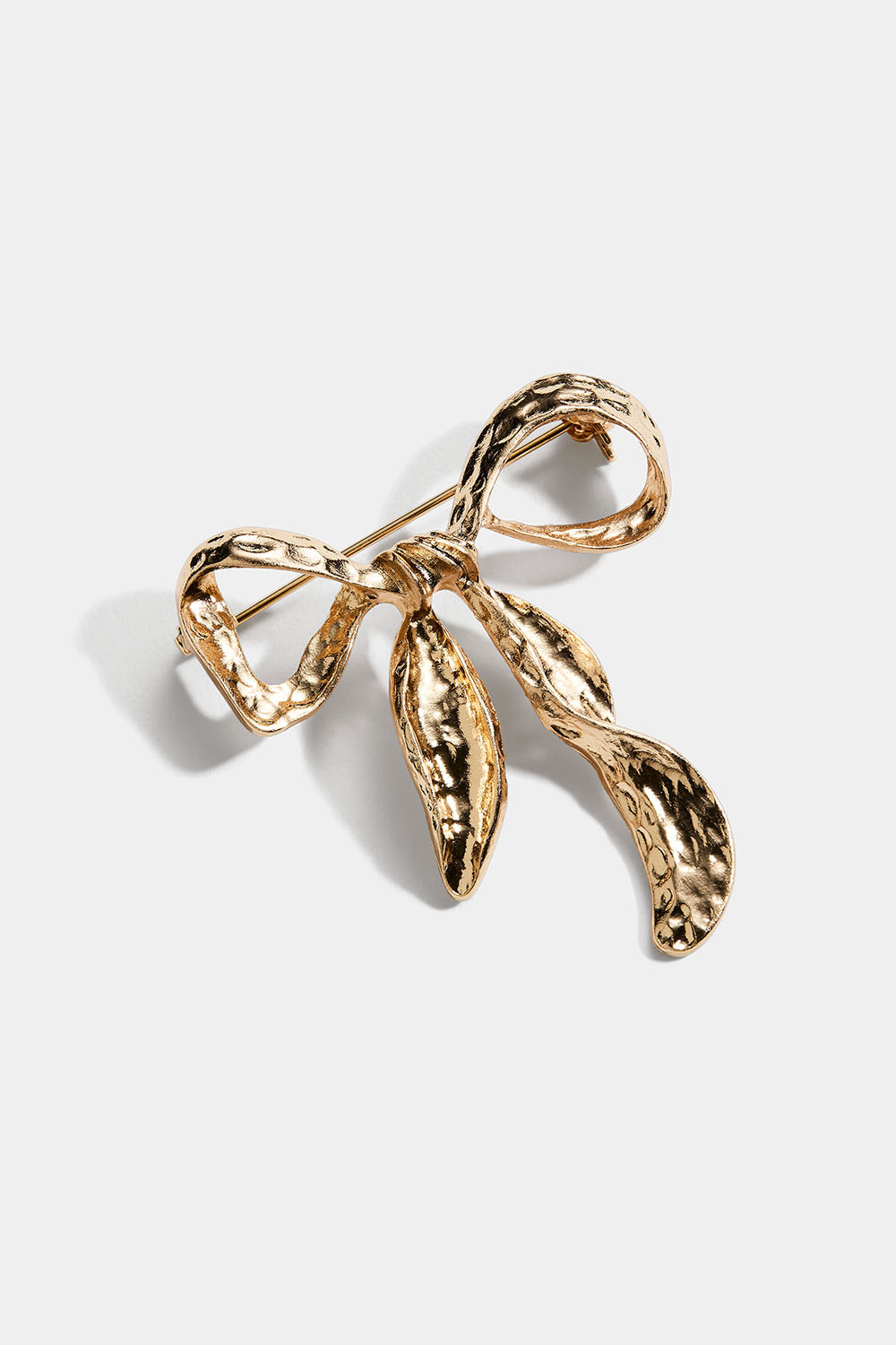 Kullanvärinen rintaneula, jossa on vasaroitu rusetti