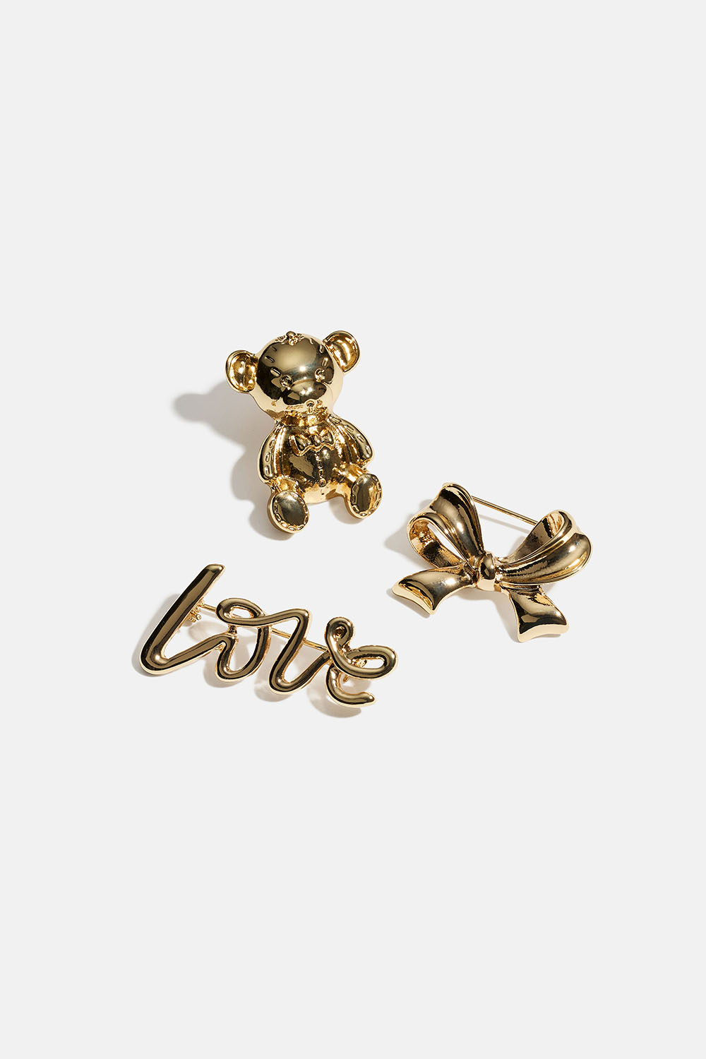 Kullanväriset rintaneulat, joissa on joko rusetti, karhu tai Love, 3 kpl