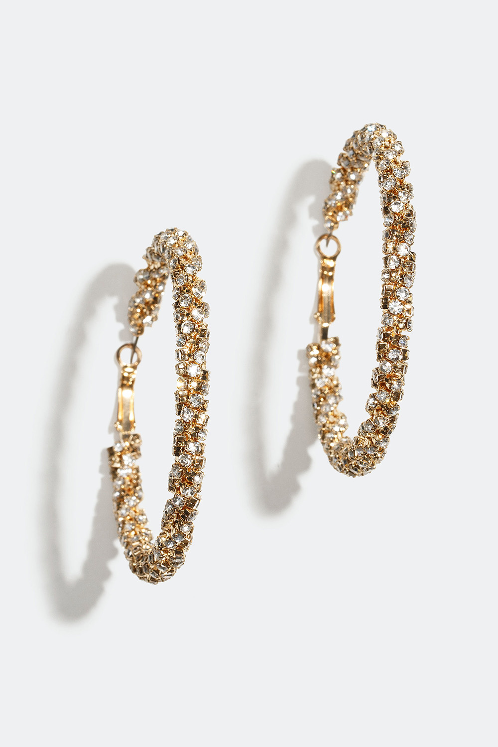 Suuret kullanväriset korvarenkaat, joissa kierrettyjä lasikiviä