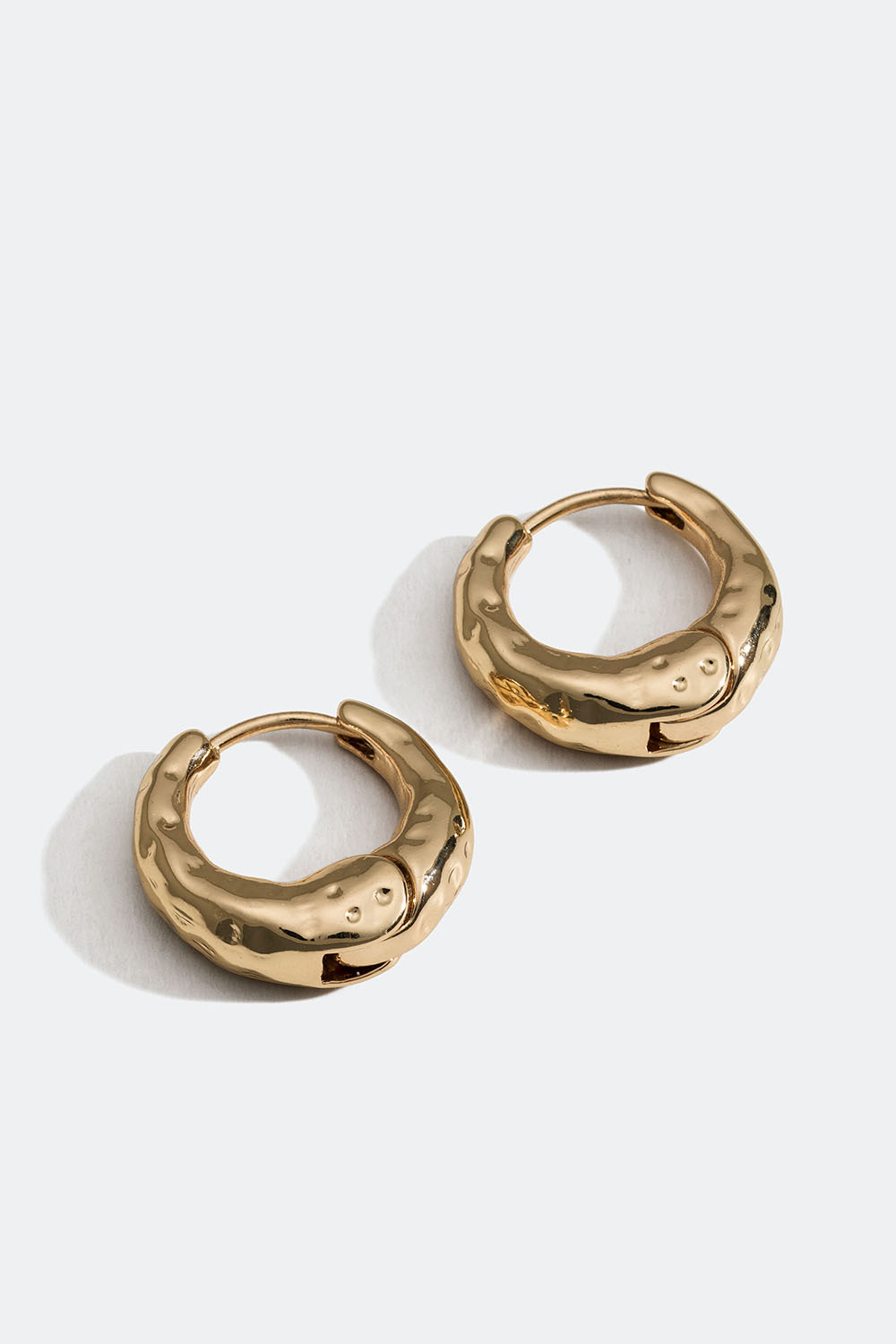 Pienet, muodoltaan muhkeat kullanväriset korvarenkaat, joiden pinta on rikottu.