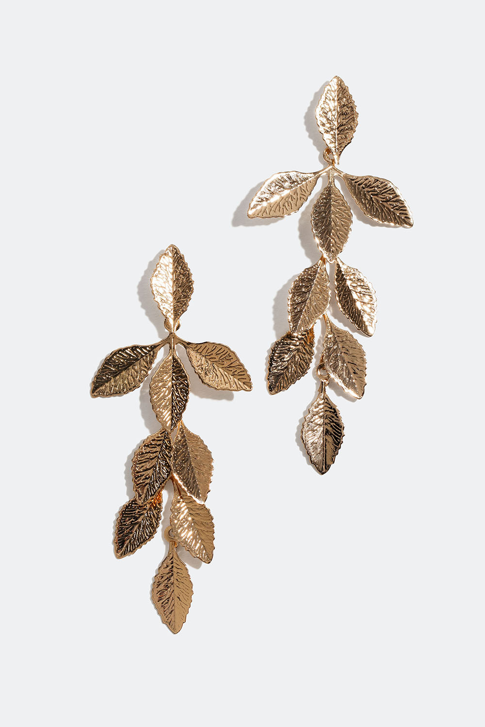 Pitkät kullanväriset korvakorut, joissa lehtiä