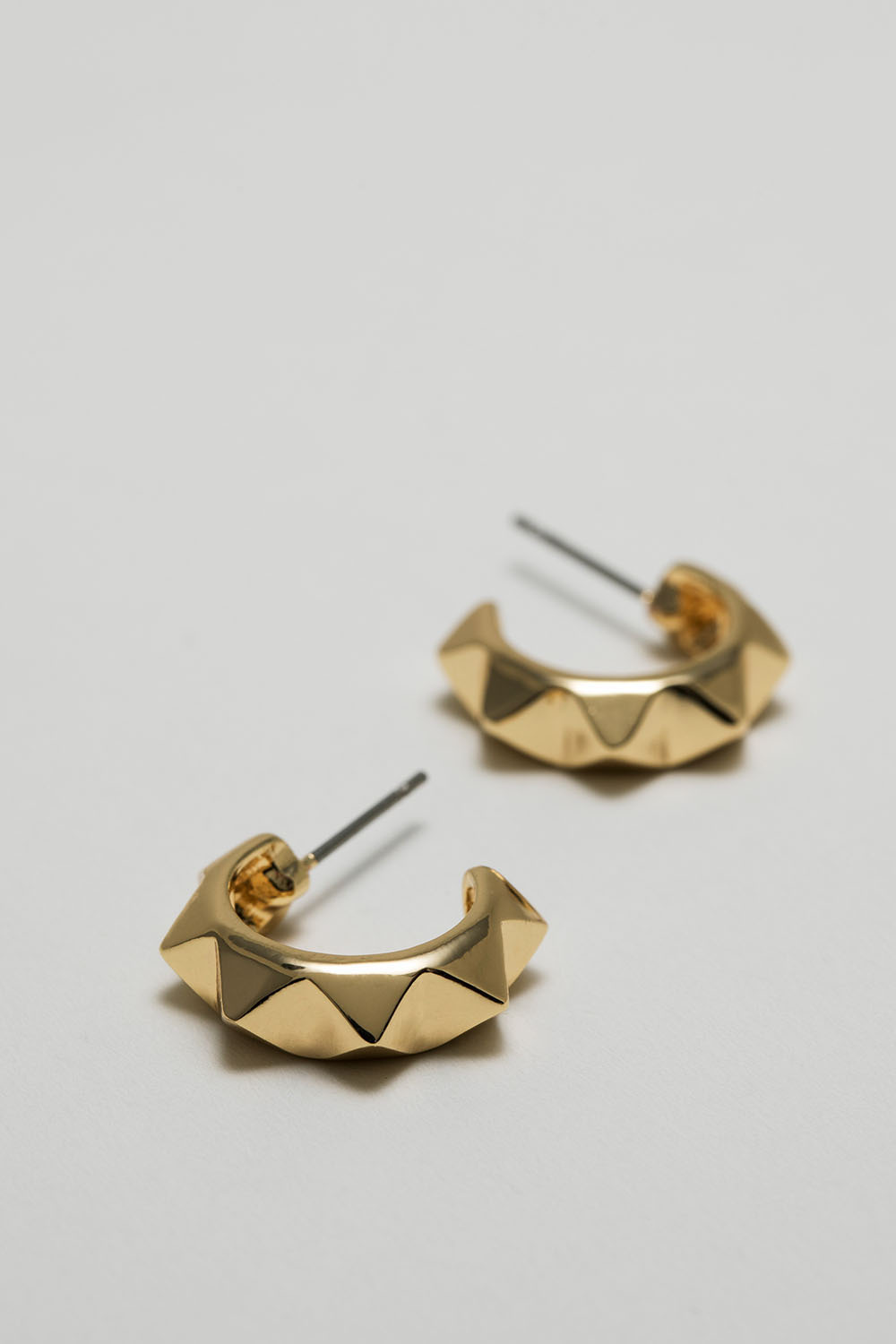 Kullanväriset korvarenkaat, joissa niittejä