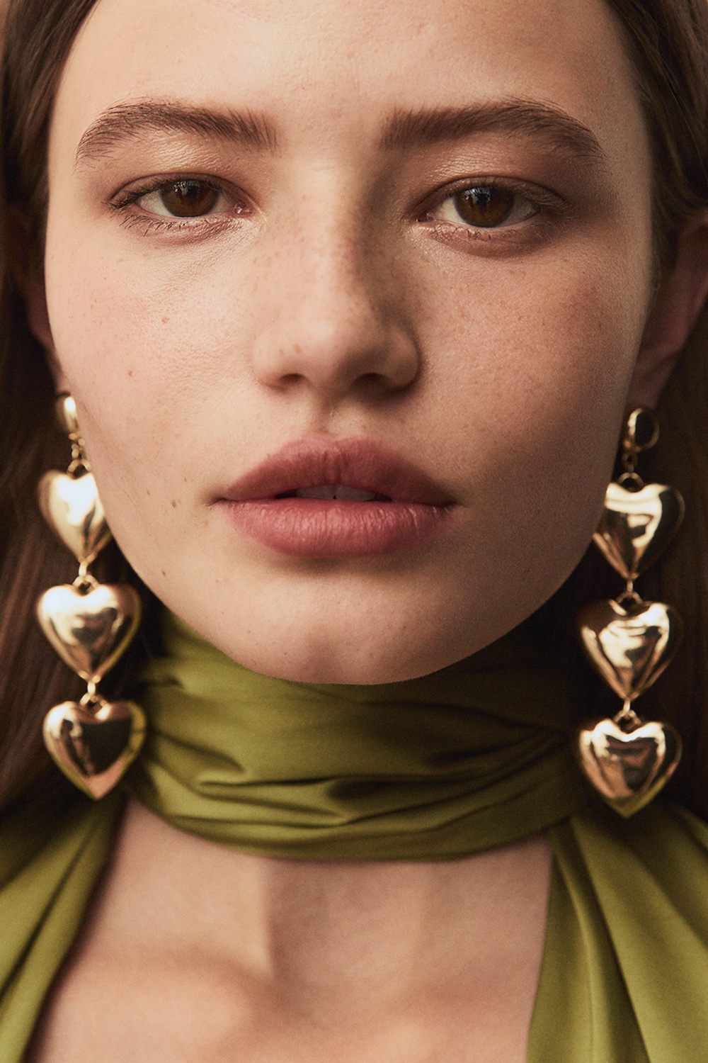 Pitkät kullanväriset korvakorut, joissa kolme sydäntä