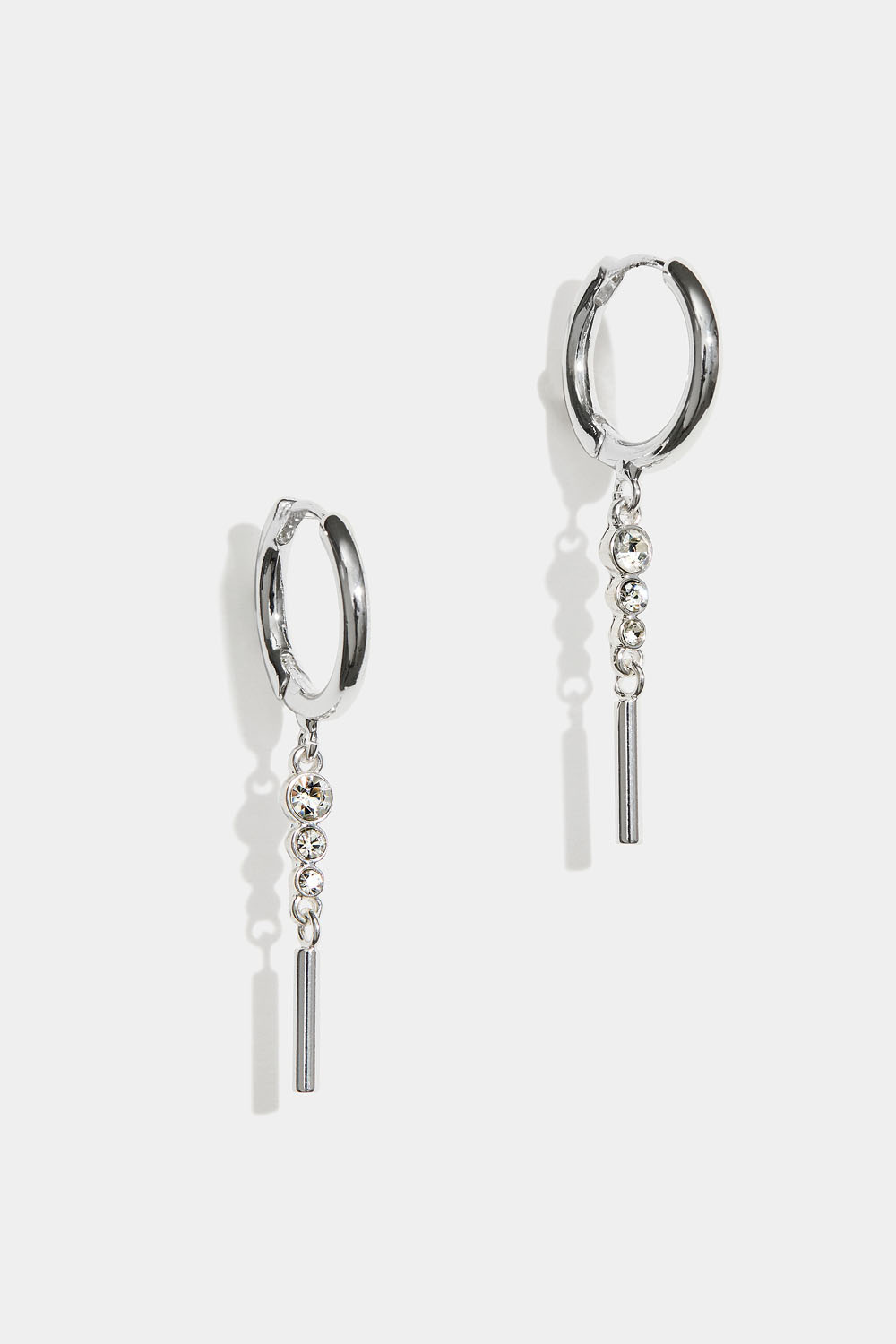 Korvarenkaat, joissa roikkuu strassikiviä ja sauva.