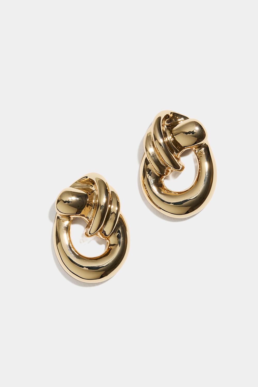 Soikeat kullanväriset korvakorut, joissa solmu