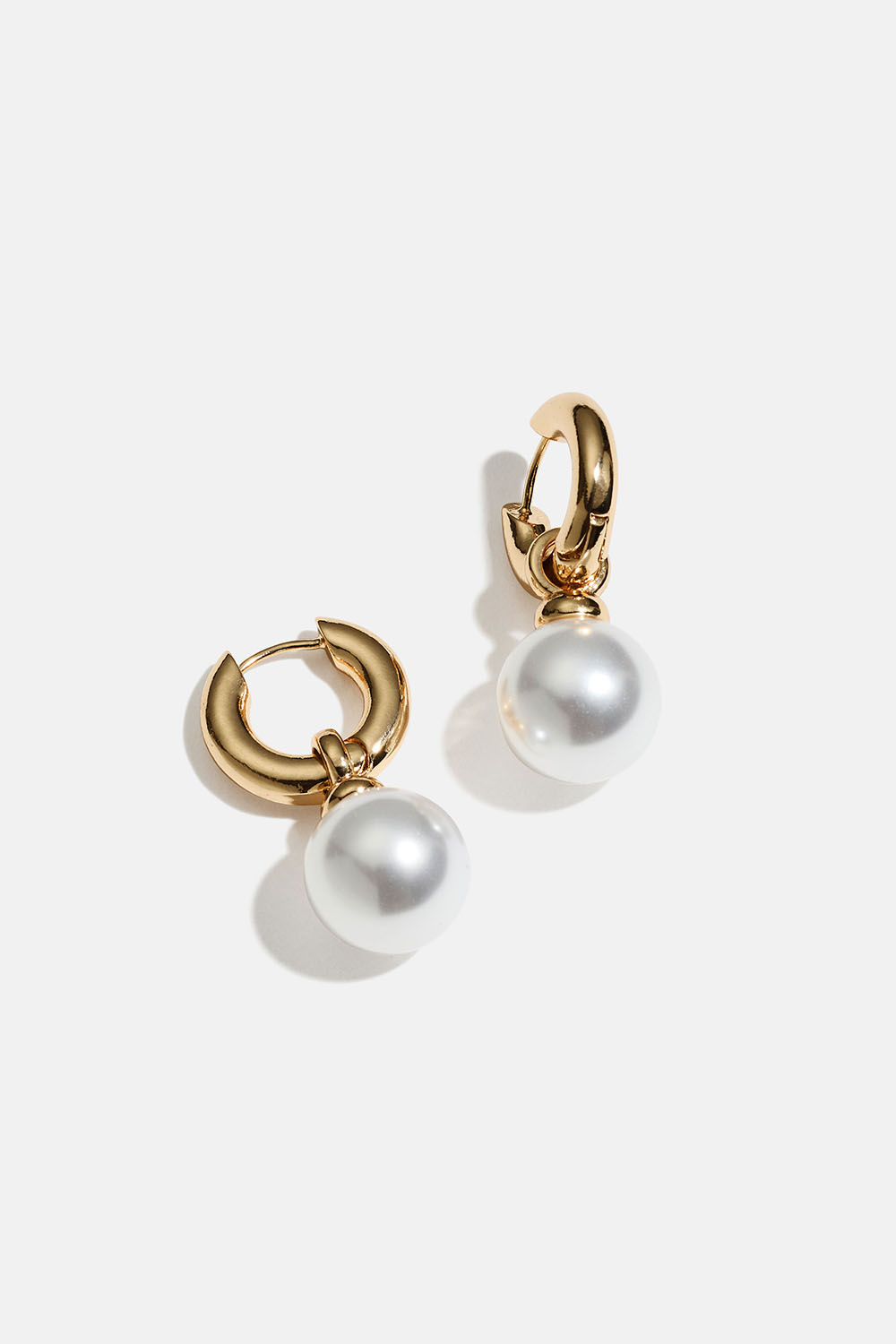 Paksut kullanväriset korvarenkaat, joissa on iso pyöreä helmi