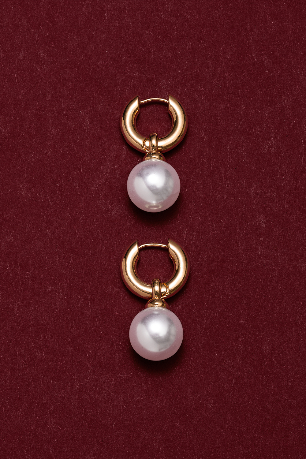 Paksut kullanväriset korvarenkaat, joissa on iso pyöreä helmi