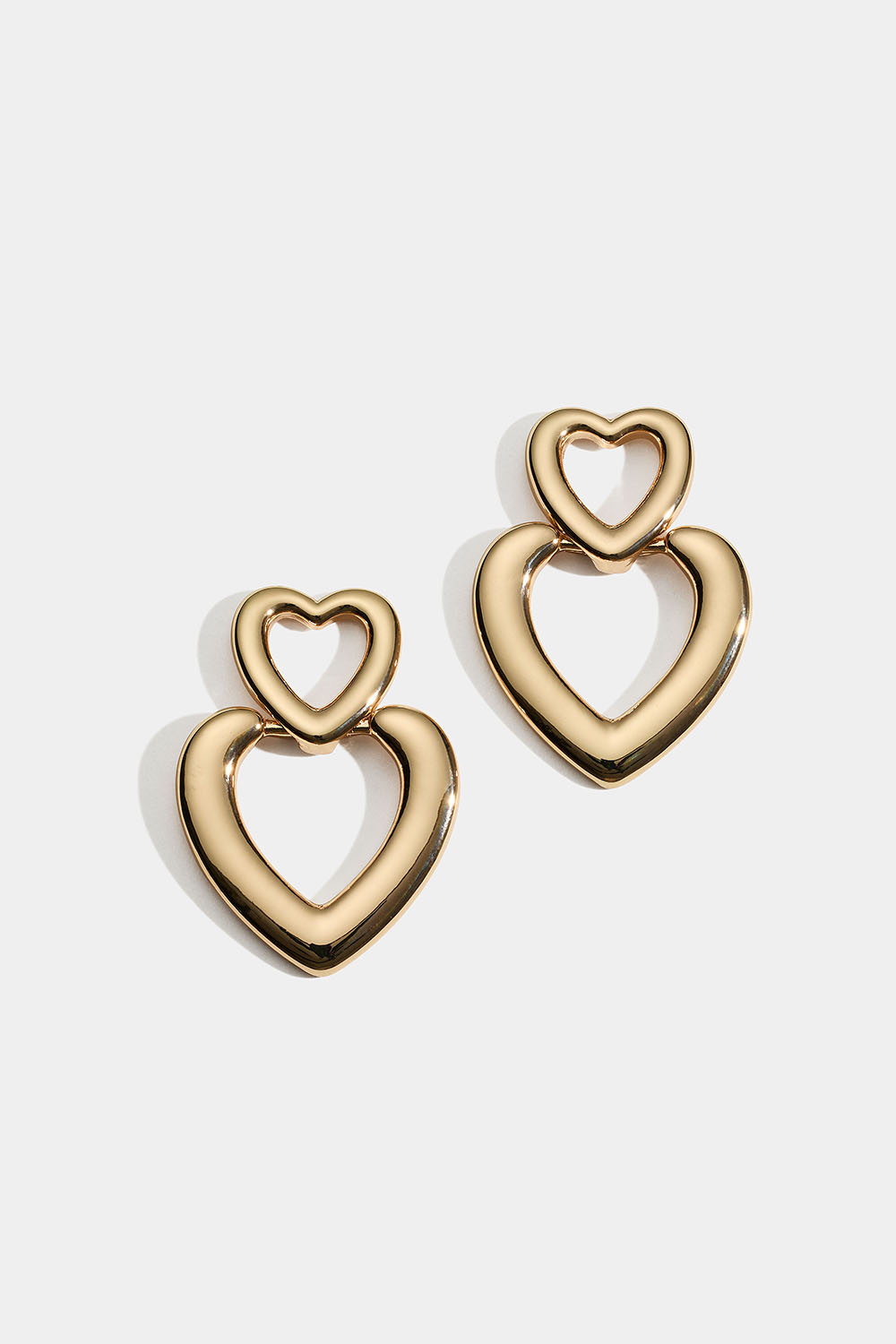 Kullanväriset korvakorut, joissa kaksi sydäntä