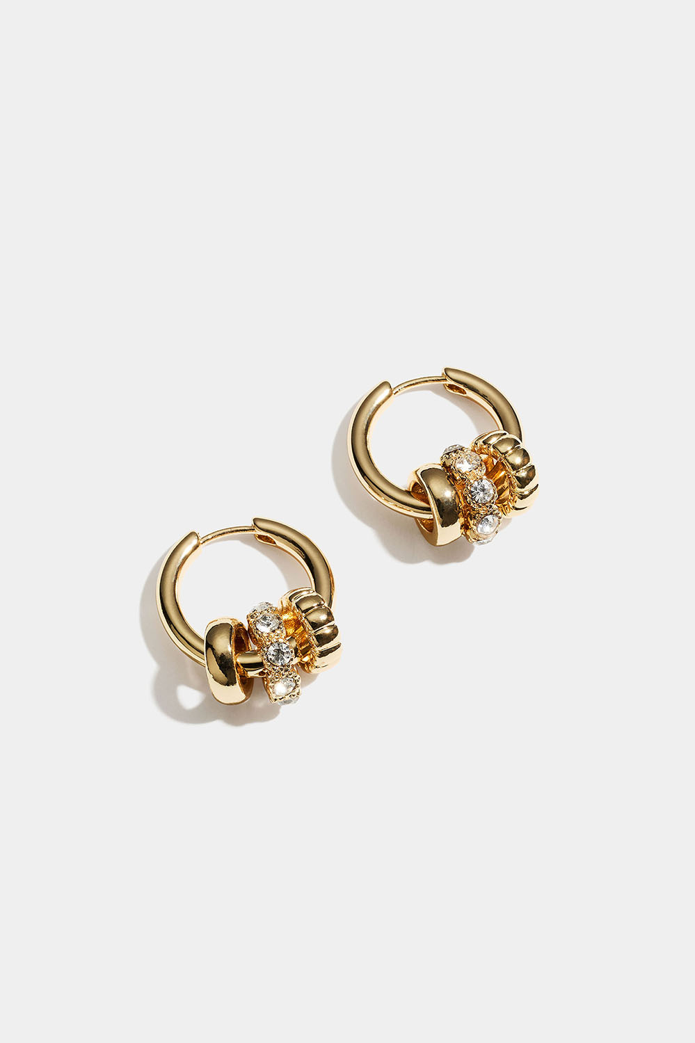 Kullanväriset korvarenkaat, joissa pyöreitä riipuksia ja lasikiviä