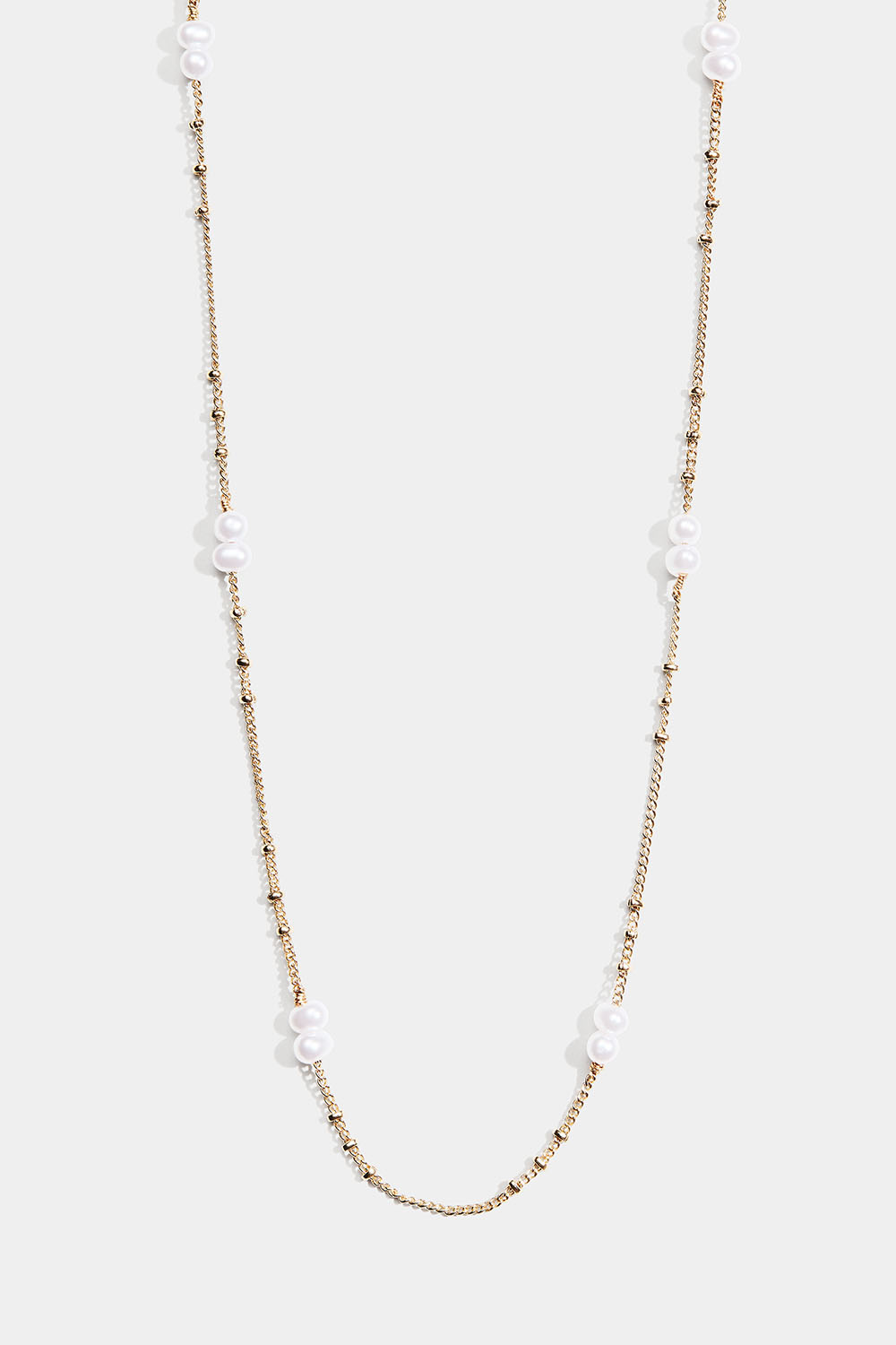 Ohut kullanvärinen kaulakoru, jossa on soikeita valkoisia helmiä