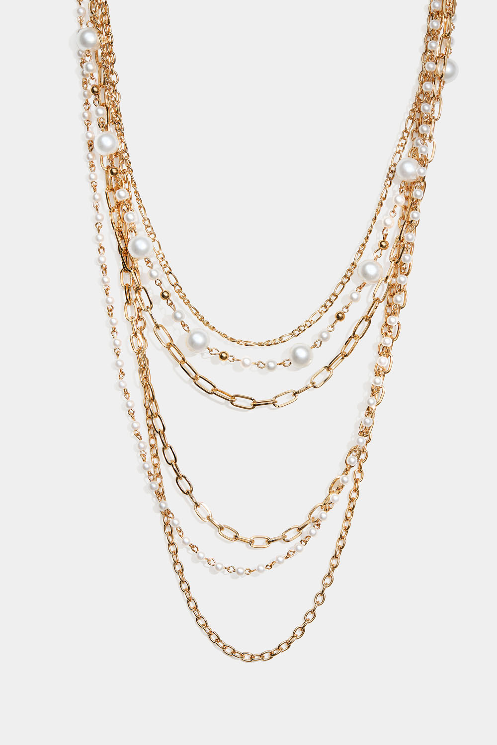 Pitkä kullanvärinen kaulakoru, jossa helmiä ja erilaisia ketjuja