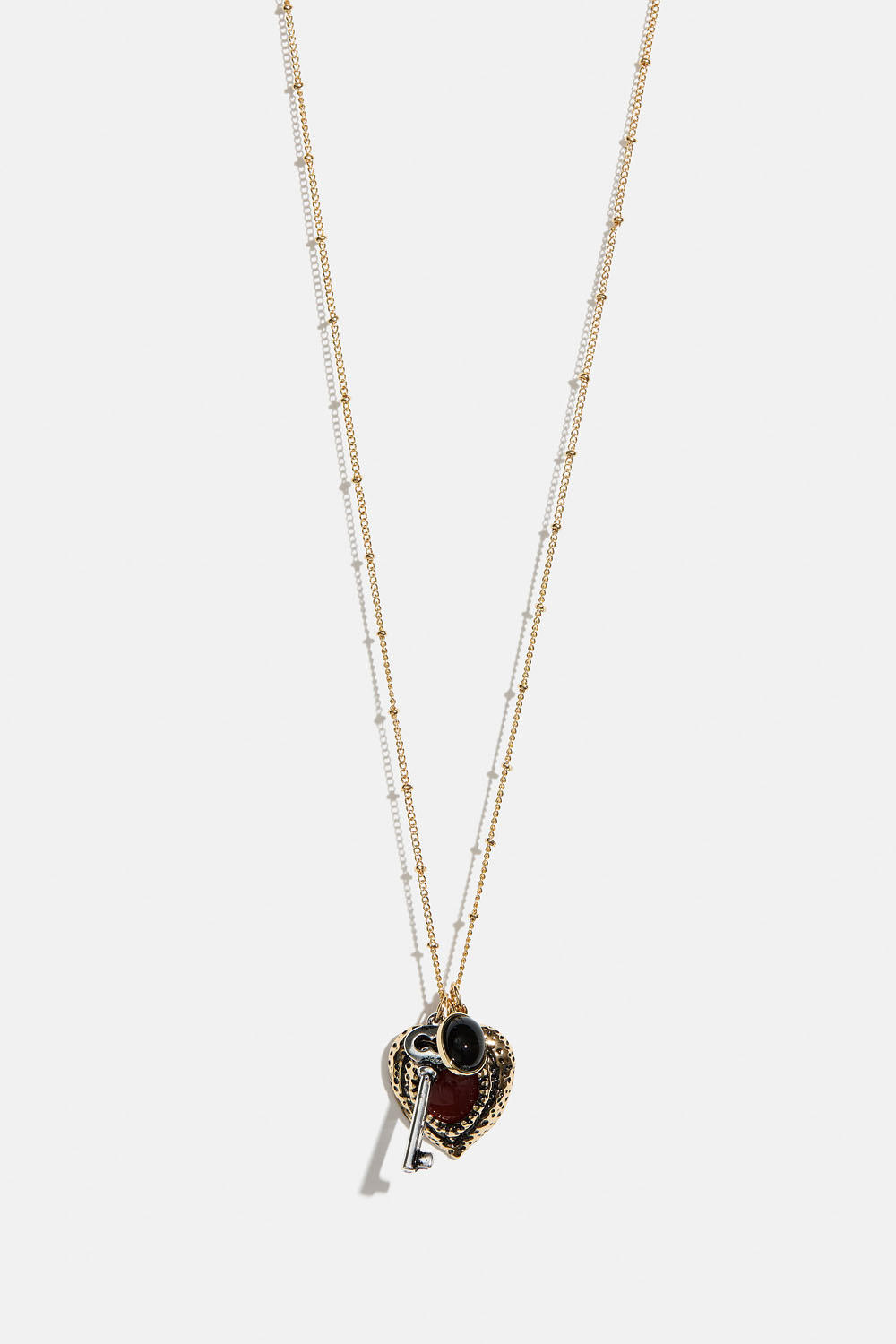 Pitkä kaulakoru, jossa sydän- ja avainriipuksia