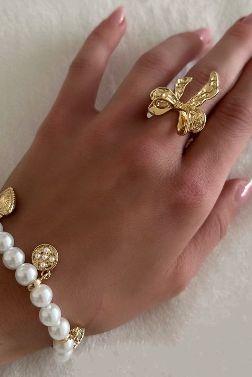 Kullanvärinen sormus, jossa on vasaroitu rusetti