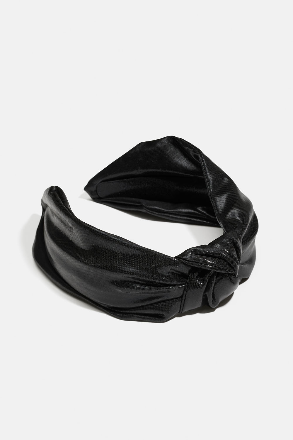 Kimaltavasta kankaasta valmistettu hiuspanta, jossa on solmu.