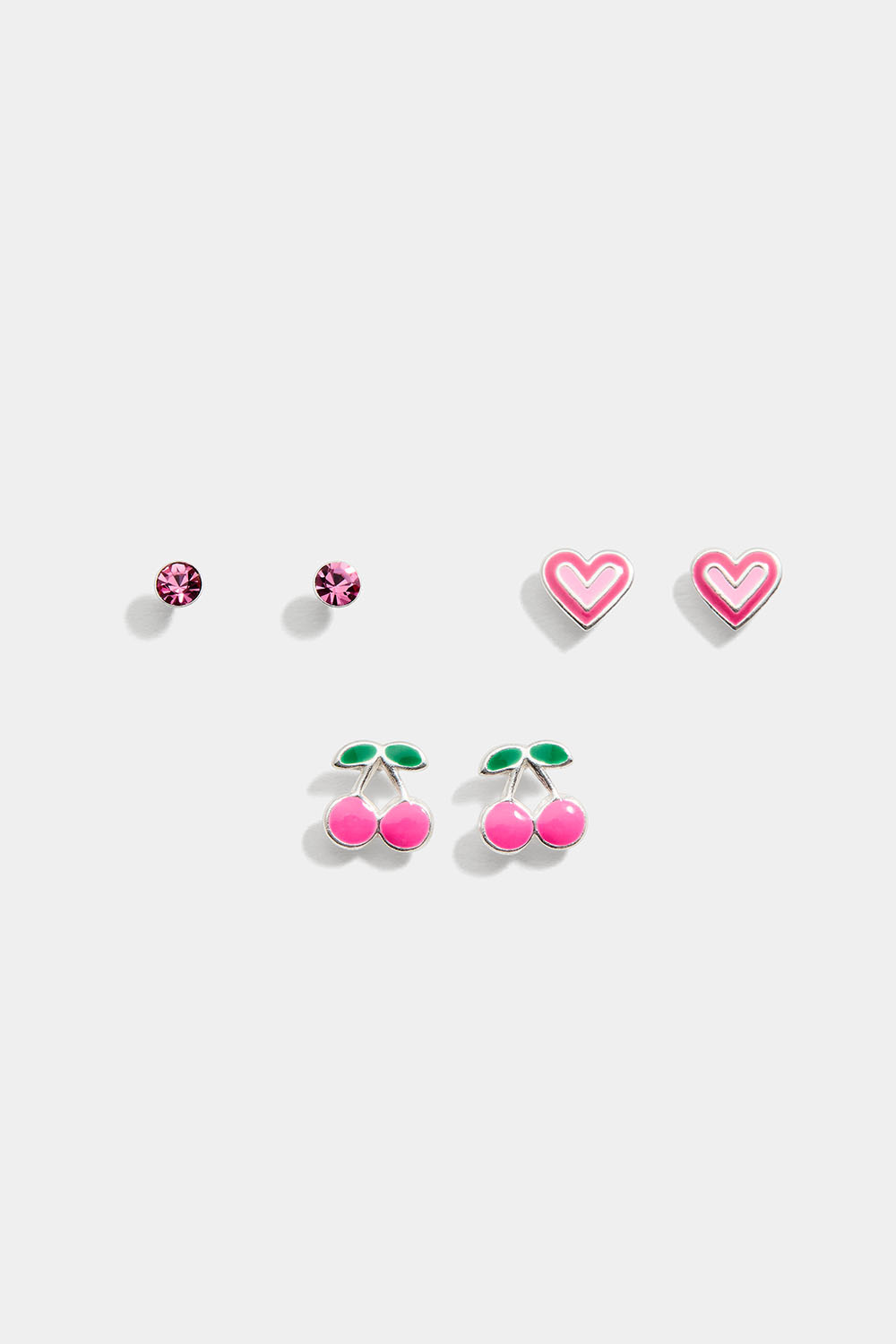 Kolme paria aitoja hopeisia korvakoruja, joissa vaaleanpunaiset kivet, sydämiä ja kirsikoita